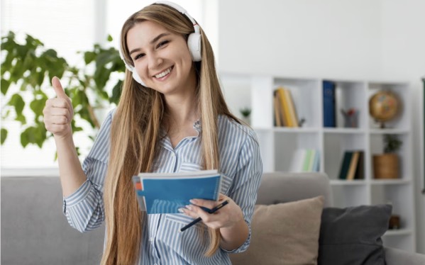 Chica estudiando idiomas con auriculares y libreta